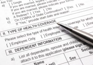 Close-up photograph of an employee group health insurance application form with pen.
